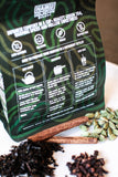 Tea package with green tea leaves, cinnamon sticks, and cloves on a white surface